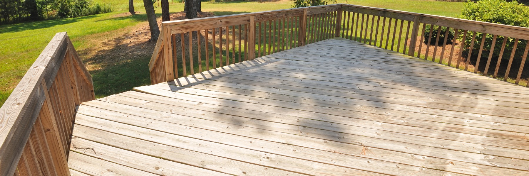 Large backyard wood deck with railing